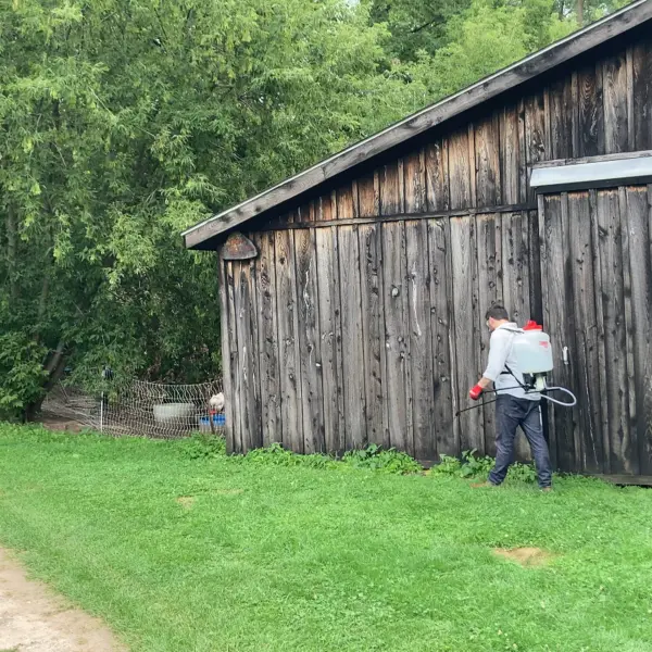 Chapin 61800 spraying weeds around a barn