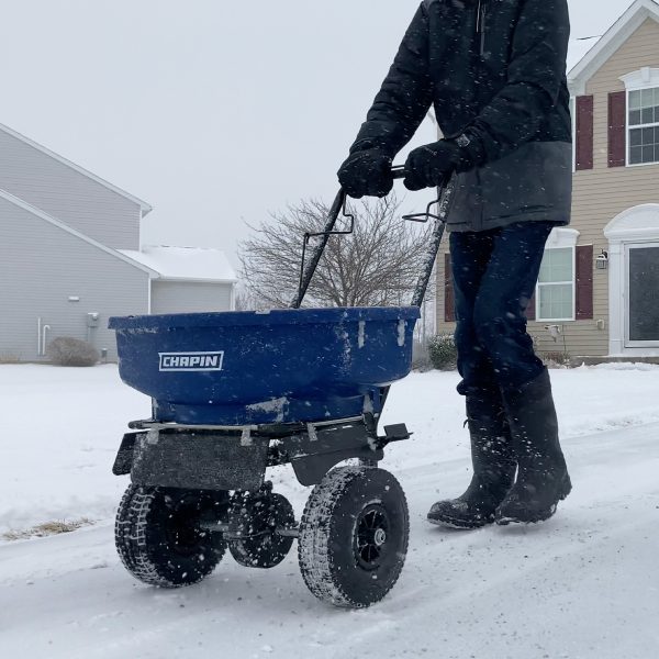 Chapin 81008A 80 Pound Residential Ice Melt Spreader in use spreading ice melt on driveway