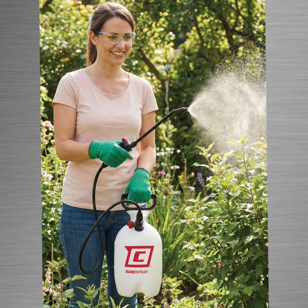 Woman spraying plants in a garden with a Chapin 20000 SureSpray garden sprayer