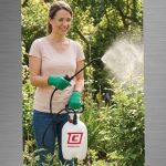 Woman spraying plants in a garden with a Chapin 20000 SureSpray garden sprayer
