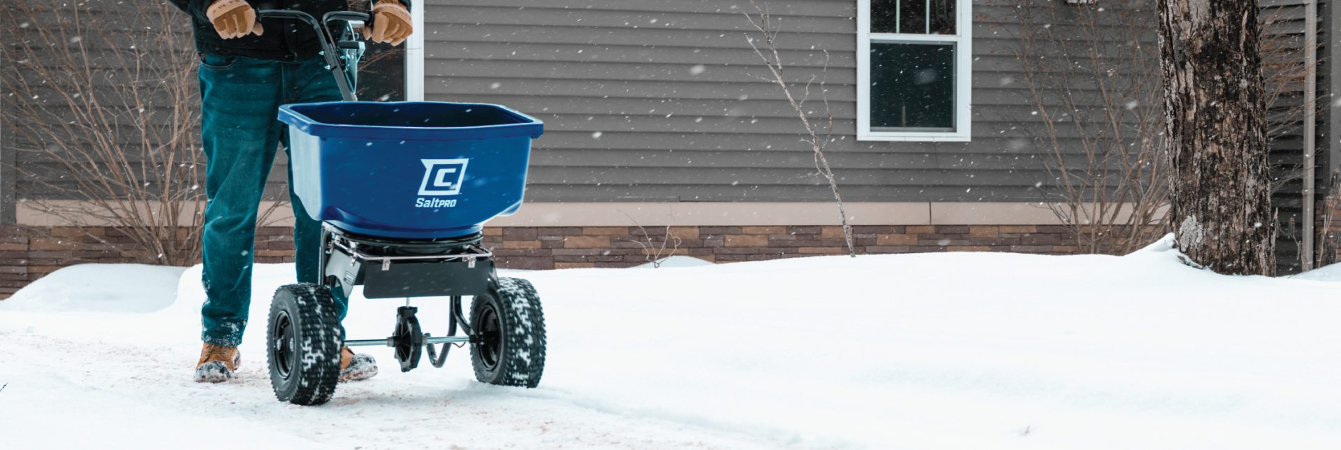 Chapin SaltPro spreader spreading salt on a winter, snowy driveway